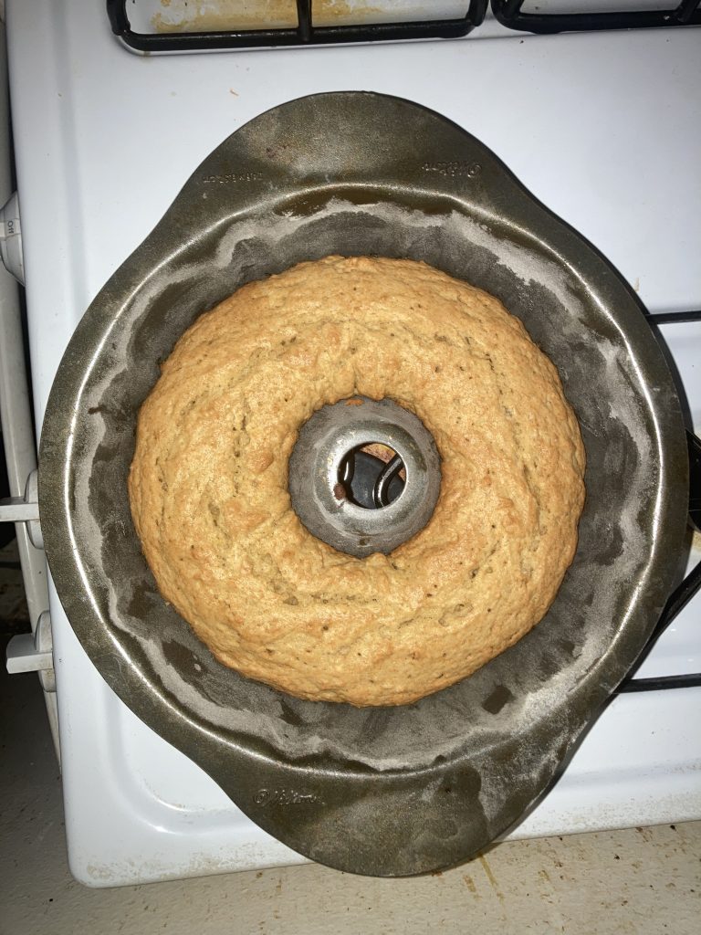 Top view of a whole lemon pound cake in a bundt pan on a stove.