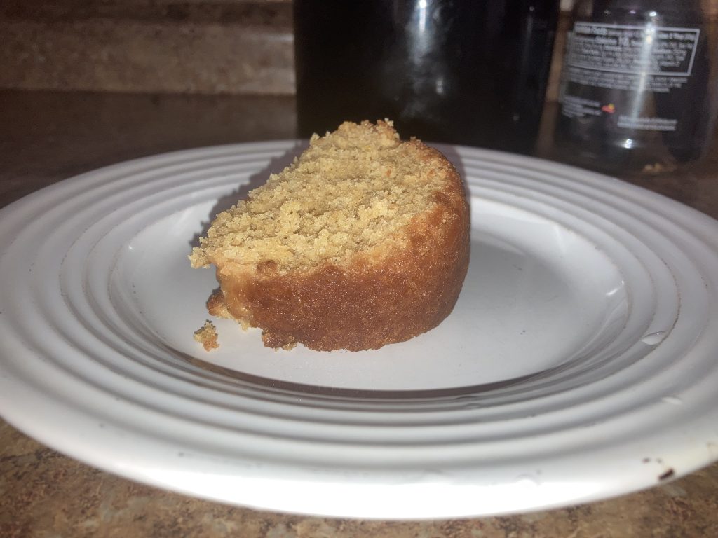 Close up view of lemon pound cake slice on a white plate on a kitchen counter.